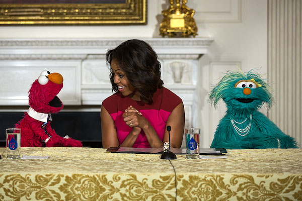 First Lady Michelle Obama, with Sesame Street Muppets Elmo and Rosita, makes a "Let's Move!" announcement about marketing healthier foods to children, in the State Dining Room of the White House, Oct. 20, 2013. (Official White House Photo by Lawrence Jackson)
